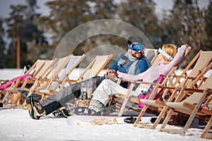 Winter holiday, ski, travel - couple relaxing together in sun at
